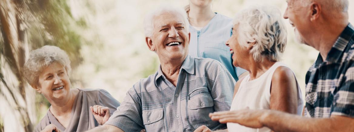 A groups of seniors laughing while sitting in a park