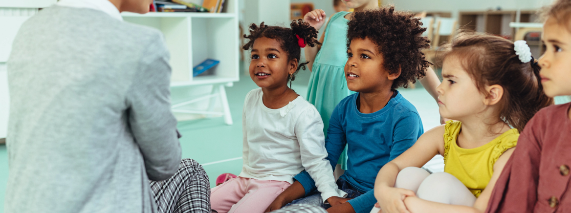A Meck Pre-K teacher is interacting with a diverse group of engaged, young students.